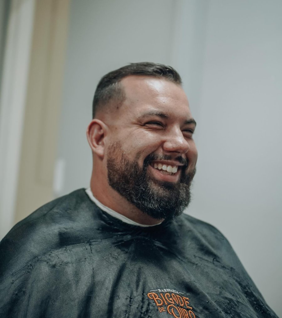 Cliente sorrindo na cadeira, com a capa da Bigode de Ouro